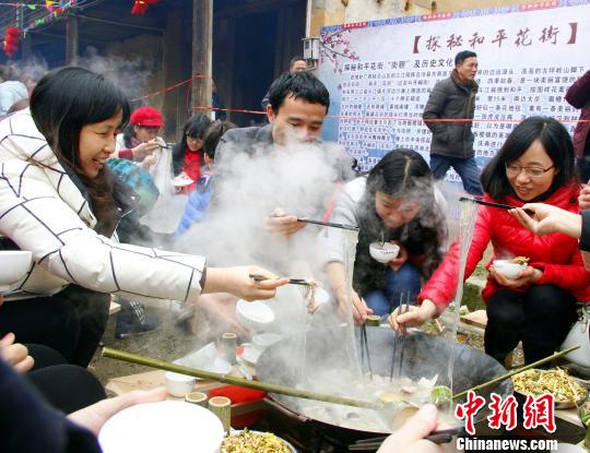 游客夹起柴火烹煮的红薯粉。　朱柳融　摄
